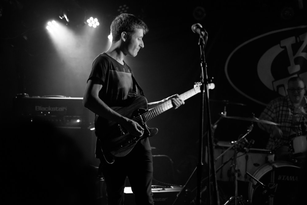 IKARI's lead guitarist Tris, on stage looking staisfied with what rock sound he's making from his guitar.