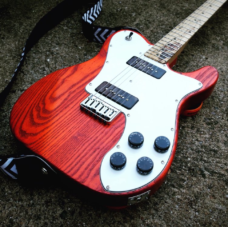 A photo of the orange stained body of an electric guitar.