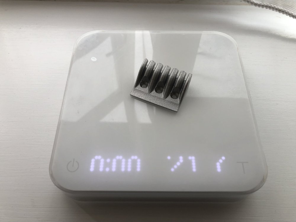 The metal 3D-printed part sits ons ome fancy coffee scales, showing something like 21.7, but you can't quite tell as the camera captures the LED update mid refresh.