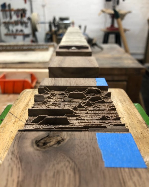 A view down a length of walnut wood, into which has been sliced a number of thin layers of wood that were then broken, so it now looks like a mountain range.