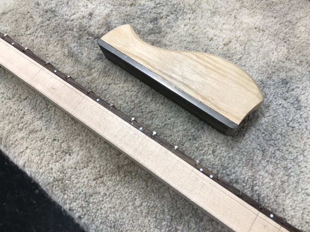 A shot of the side of the neck, where you can see the unfinished fret ends, and then beside it a file-block that I used to level them. I'm not sure what the technical term is for what I'm calling a file-block: normal files are abrasive metal sticks with a wooden or plastic handle at the end, whereas this is a metal file on the underside of block of wood so you can push it down more easily when running it along the frets.