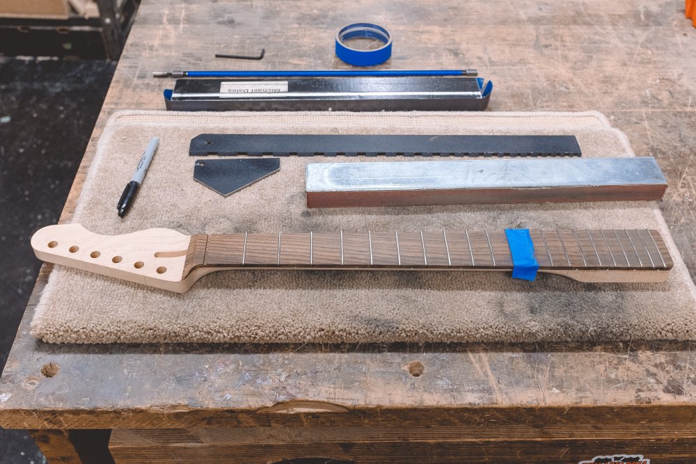 The neck being worked on looks pretty similar to the previous photo at this distance, but there is now masking tape covering the 11th and 12th frets.