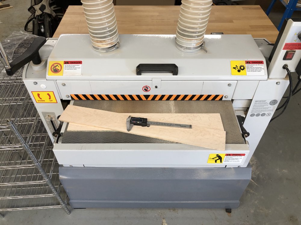 Two small planks of birds-eye maple sit on the feeder for a big machine, with a set of callipers to hand.