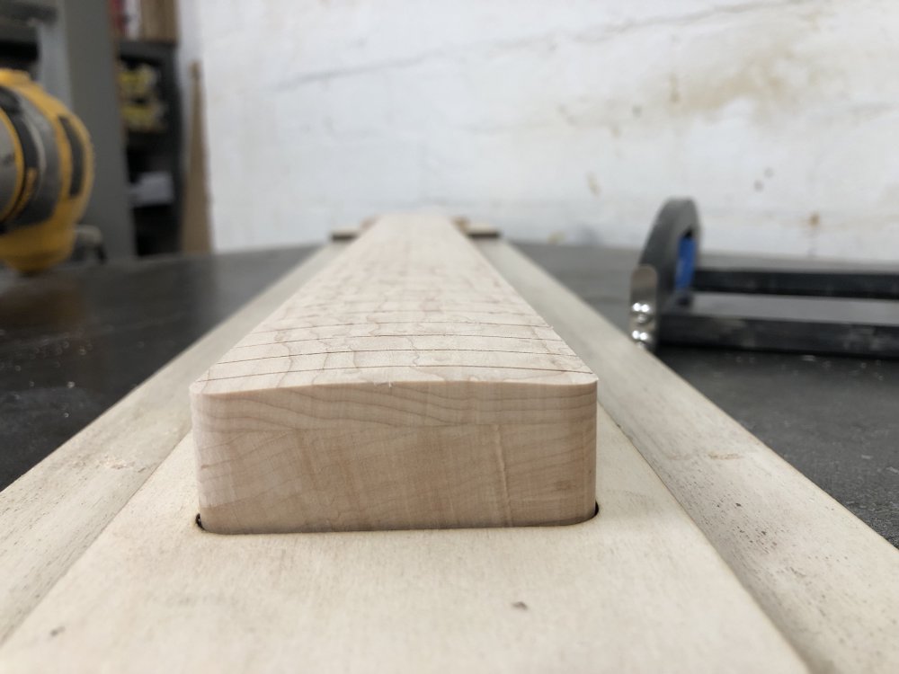 A close up view of the end of the neck, showing the top of the fretboard does indeed have a radius in it now.