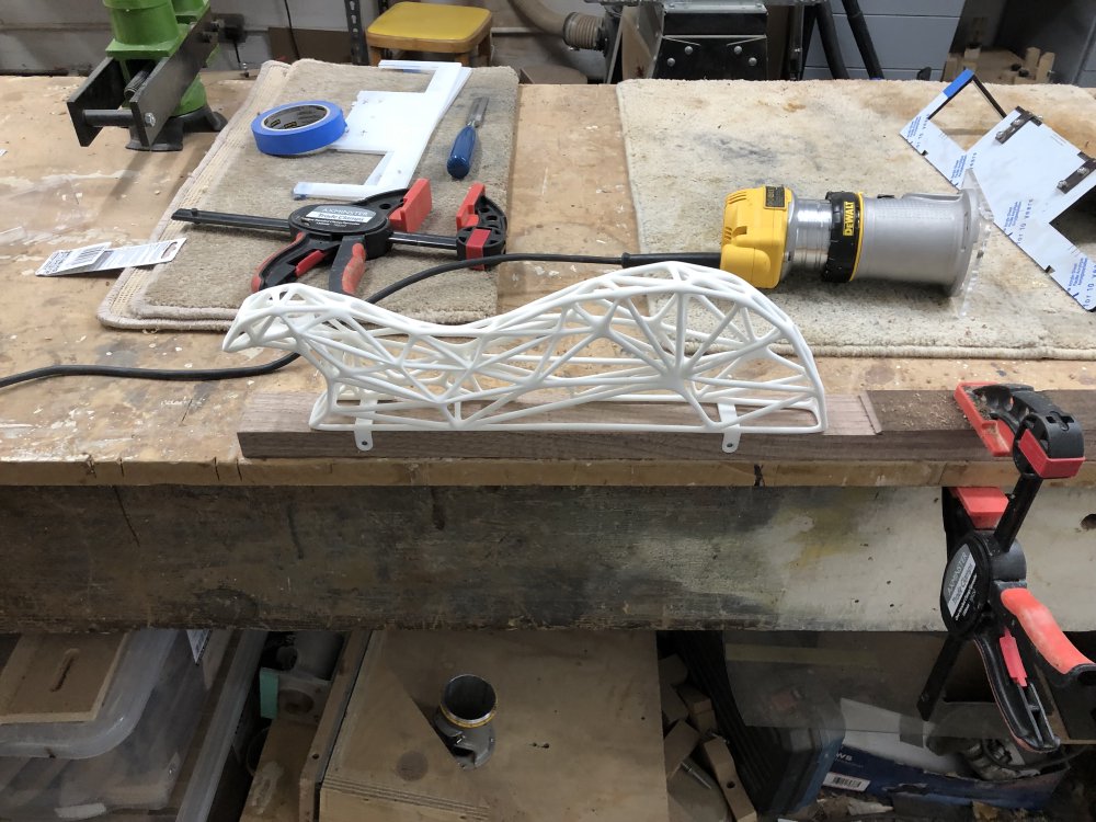 The same plank of wood with the slots in it from the previous picture, but now mounted in the slot is one side of the 3D-printed mesh guitar body.