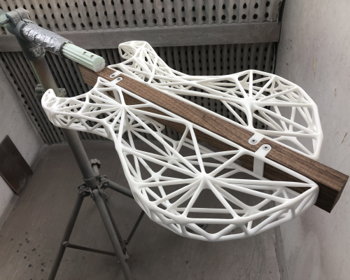 A view of the 3D-printed lattice-work guitar body in the spray booth ready to be sprayed.