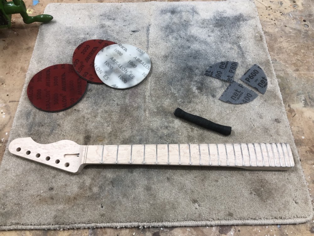 The neck sits on the workbench ready to have the sanding stage done on the neck. It's clean maple look shows through nicely, but if you look at each fret you can make out a V shape of dirt from the fret end filing.