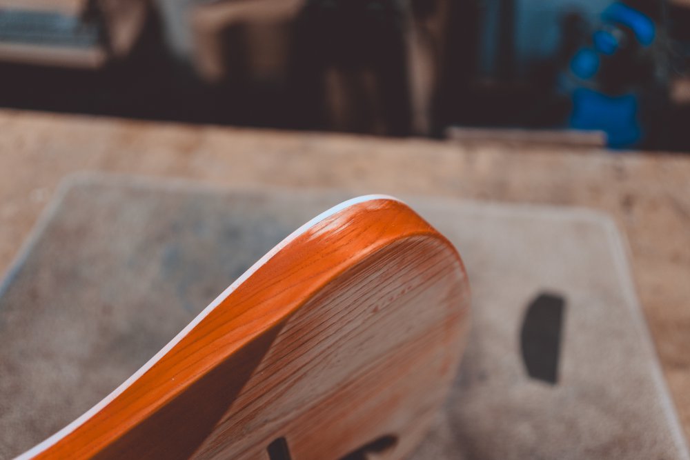 A close-up photo of the side of the guitar body, showing an area near the white binding on the side where the orange staining has been scraped away.