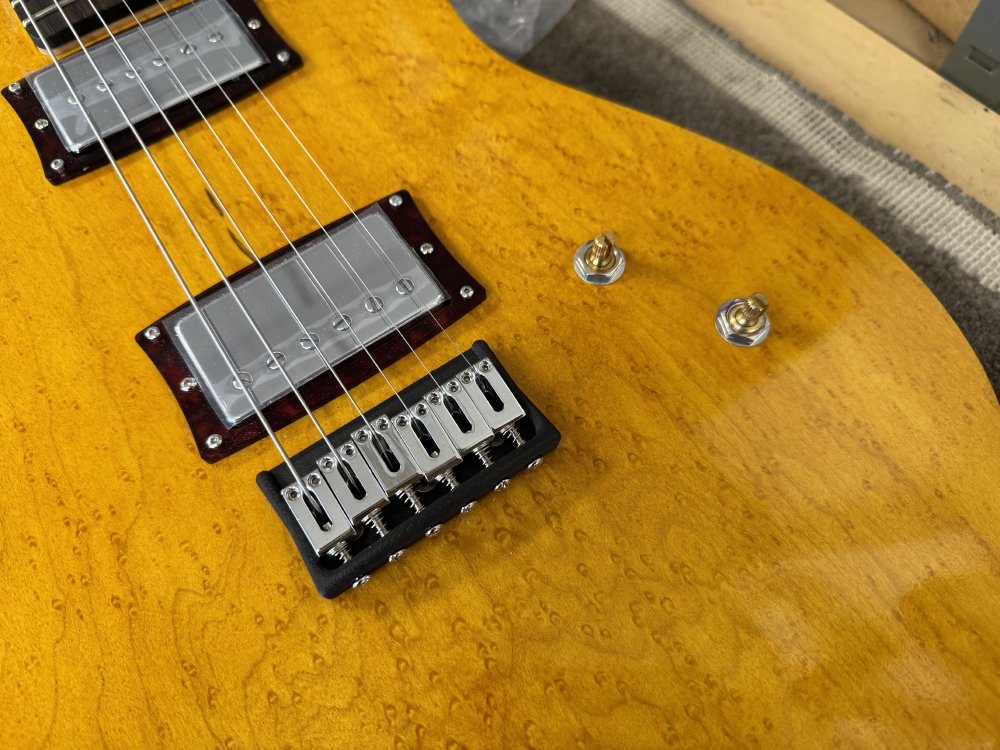 A close-up photo showing two potentiometers mounted to the front of the guitar for the volume and tone control.