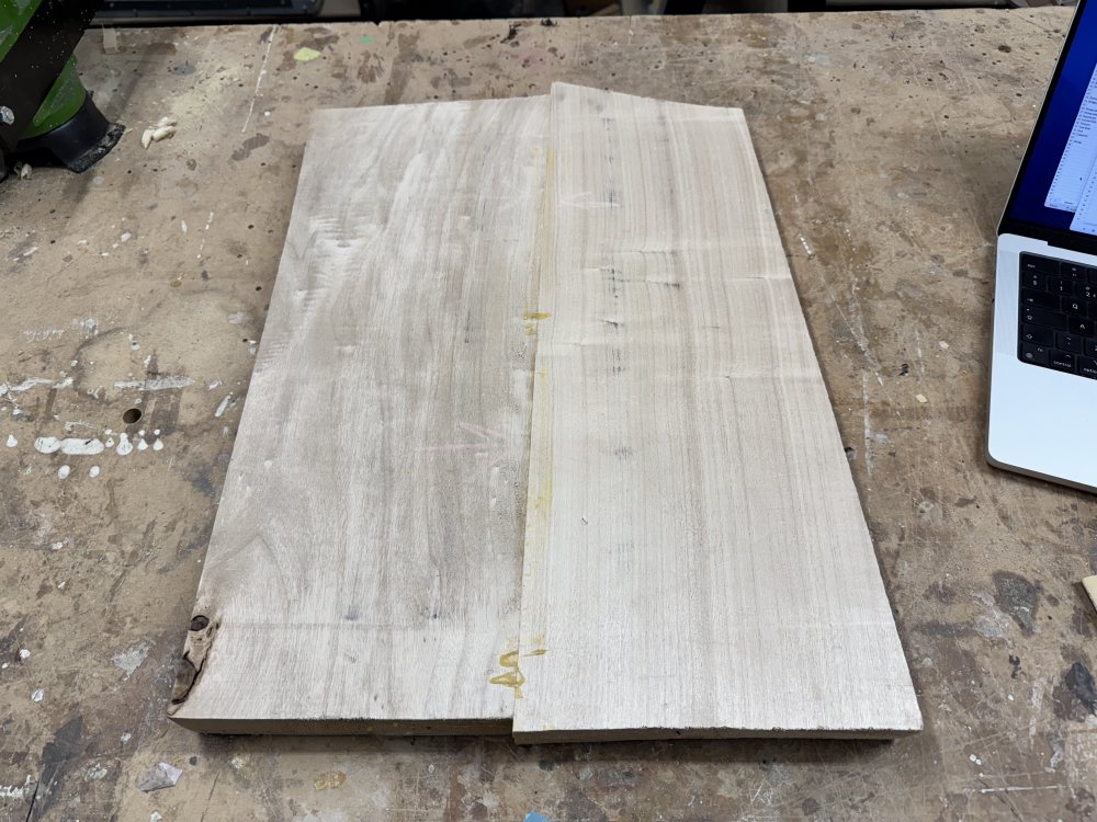 A photo of a two-piece body blank sat on a workbench. The wood is a pale wood with fairly tight grain patterns. Along the seam you can see there are still some bits of excess glue dried on.