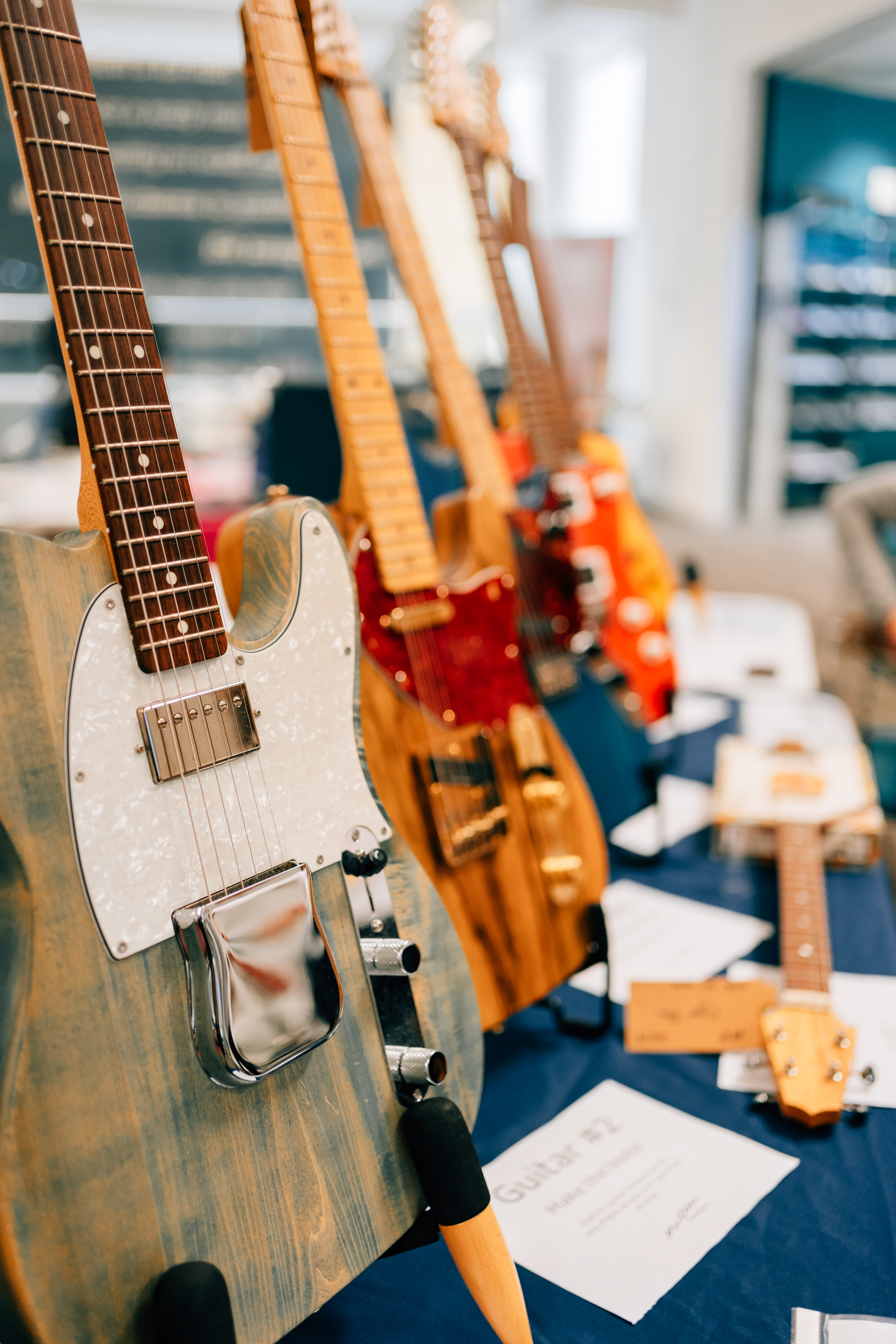 A close up photo showing the line of guitars on the table, slowly fading out of focus.