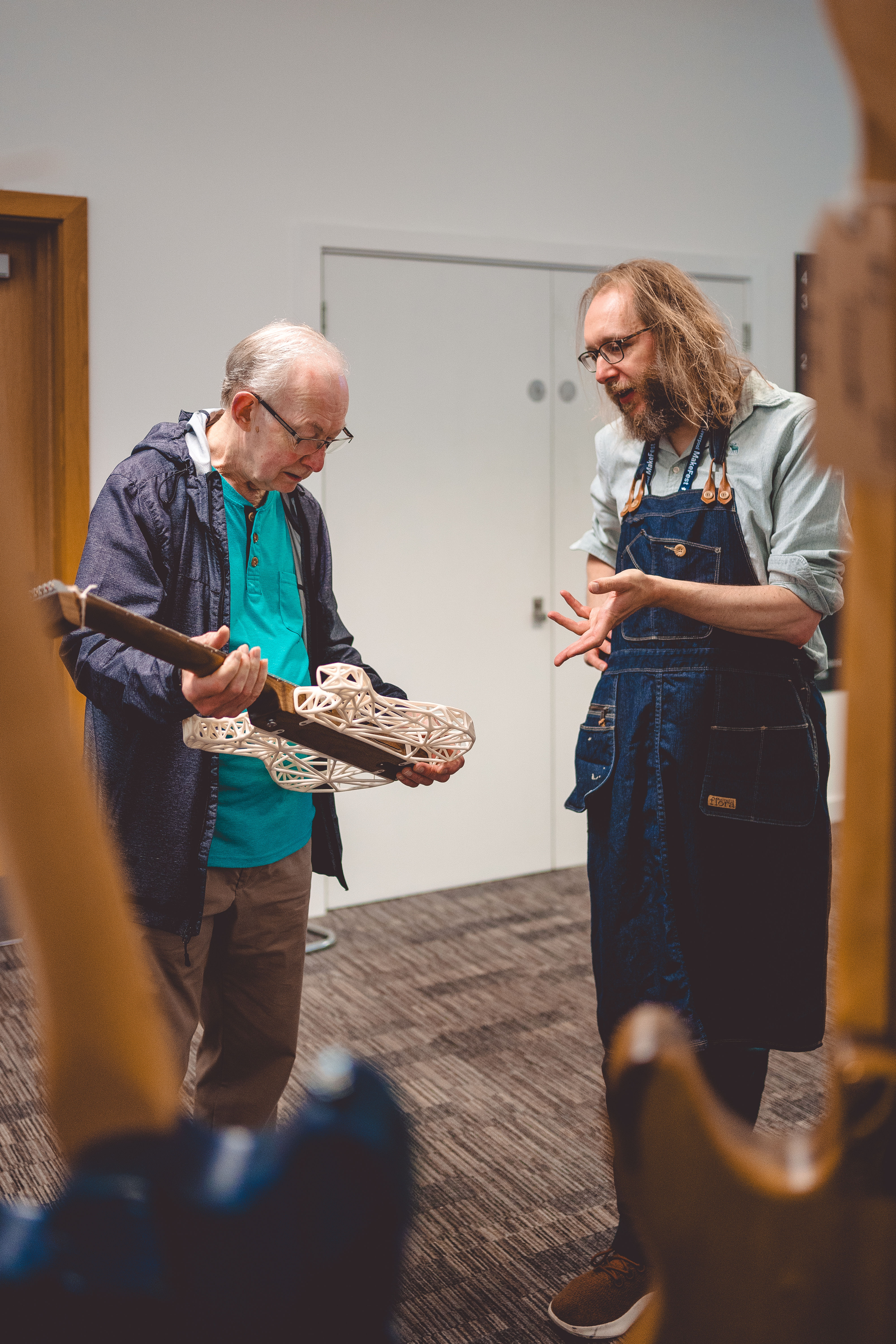 A photo of me chatting to a man who is currently holding the partially 3D-printed guitar I've made.