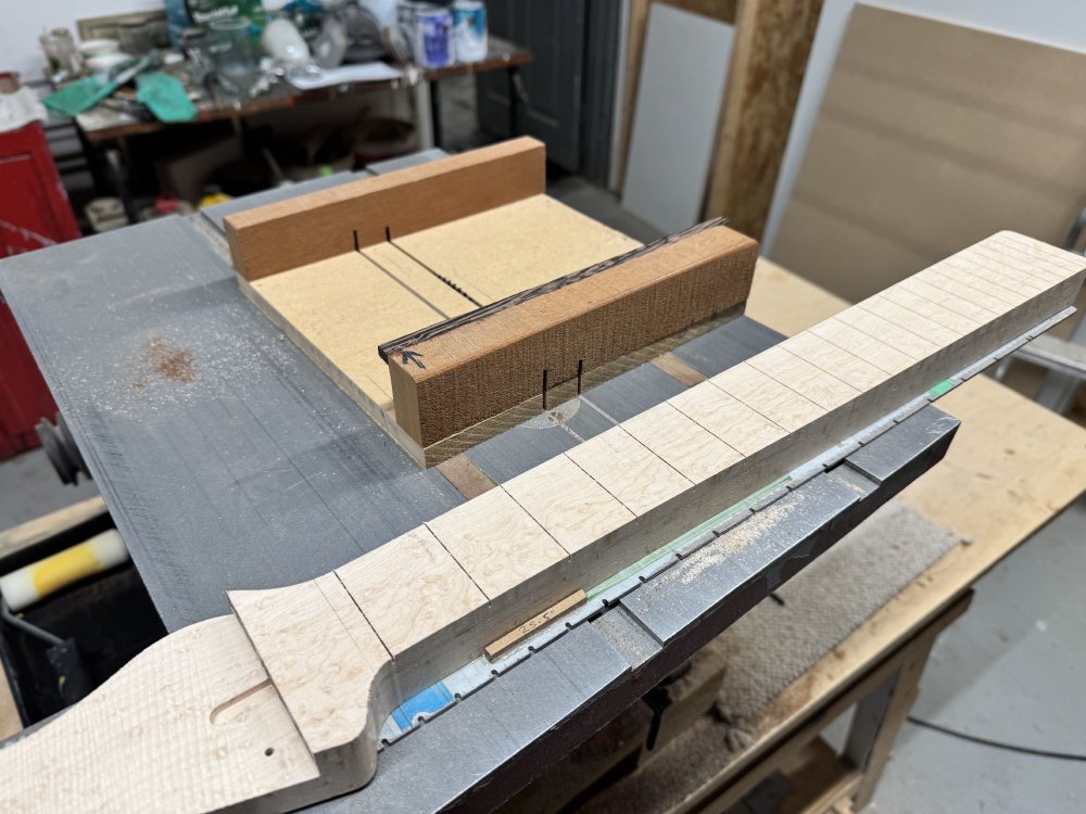 Another photo of the table-saw bed, showing that the neck now has slots cut into the fretboard where before there were none.