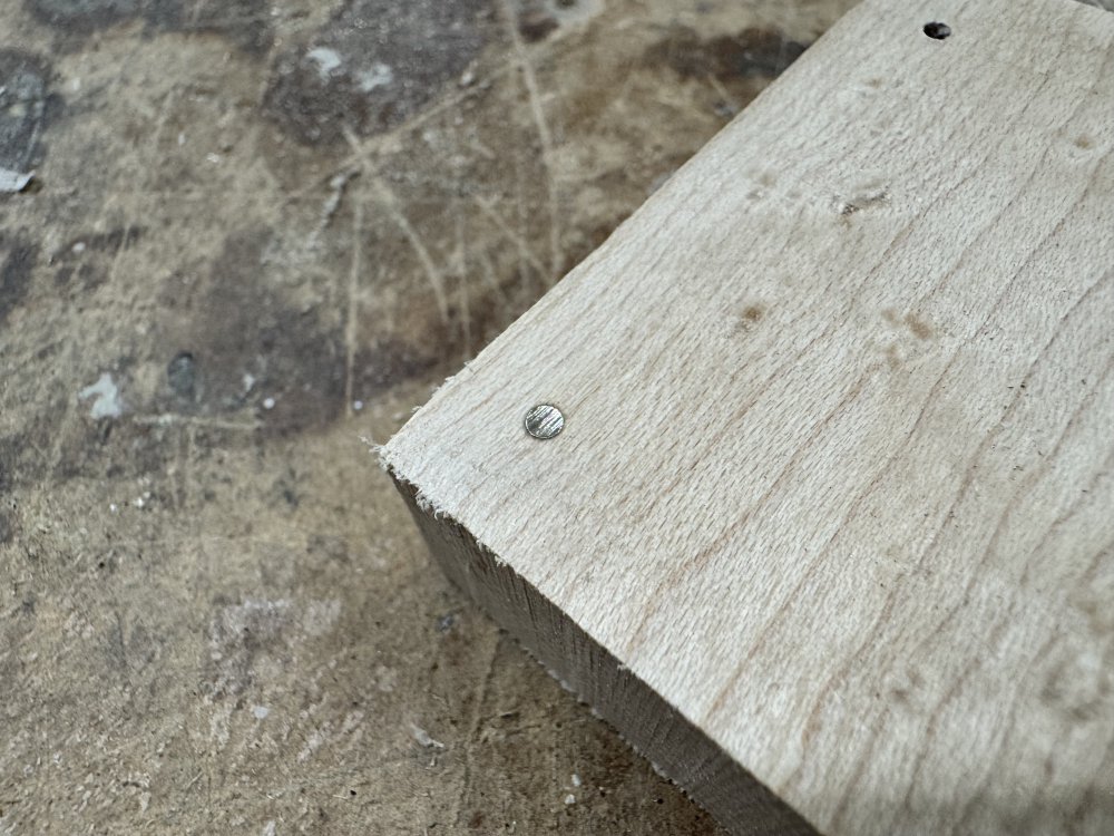 A close up photo of the maple block showing one of the holes now filled with a goldish looking metal.