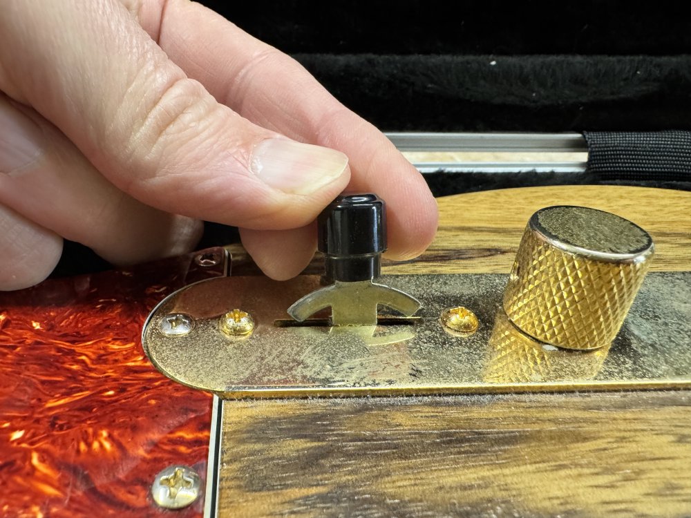 A photo showing a close look at the pickup selector switch on the guitar in the previous picture. A hand is holding the switch level which is half out of the slot it should sit in.