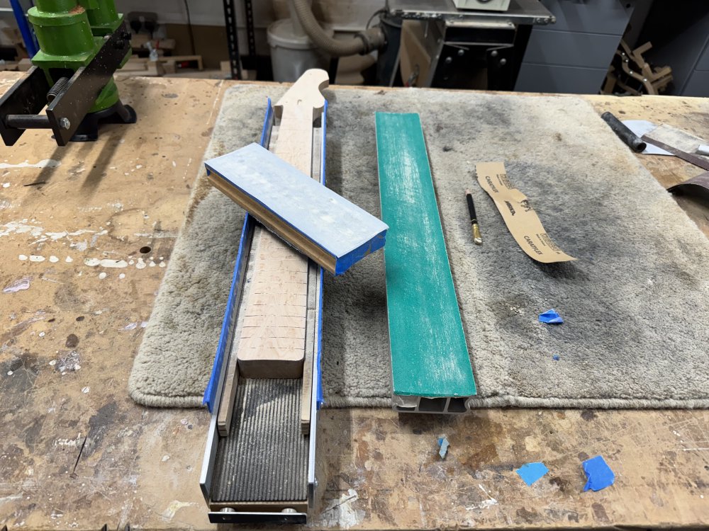 A final photo of the neck in the metal jig, with the fretboard radius now sanded into it.